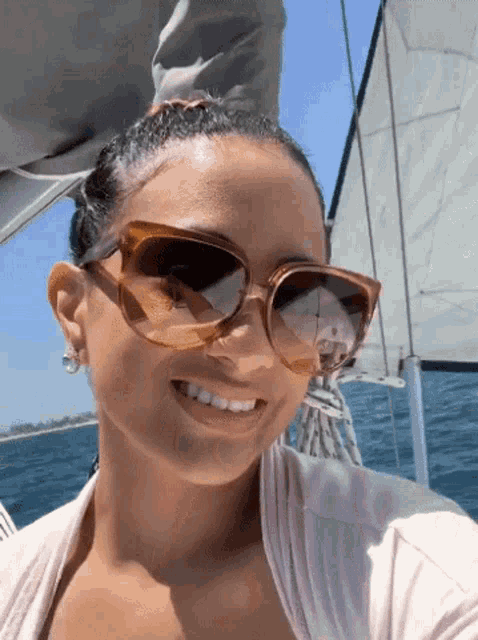 a woman wearing sunglasses smiles while on a boat