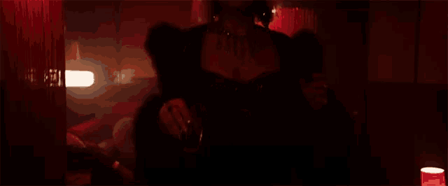 a woman is standing in a dark room with a heart on the wall