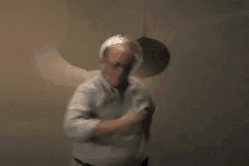 a bald man is standing in front of a disco ball hanging from the ceiling .