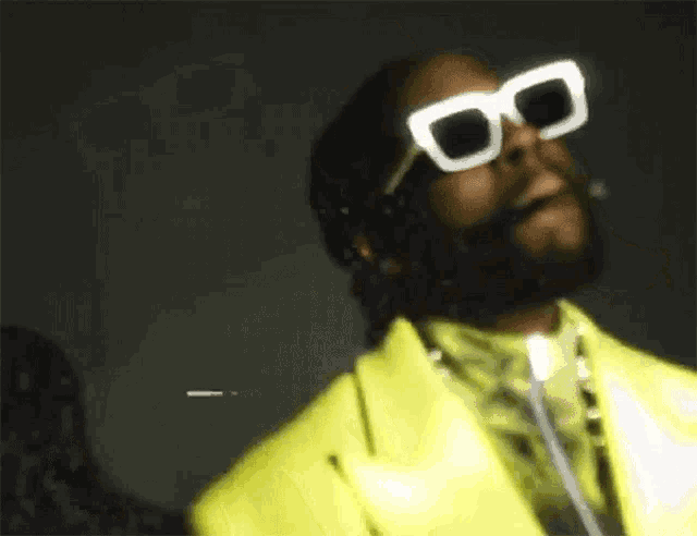 a man wearing glow in the dark sunglasses and a yellow suit is smoking a cigarette