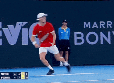 a man in a red shirt is running on a tennis court in front of a sign that says marr bon