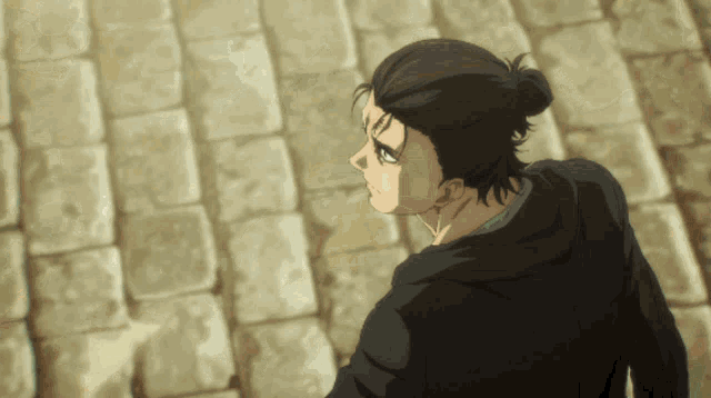 a man with a bun in his hair is standing on a brick sidewalk