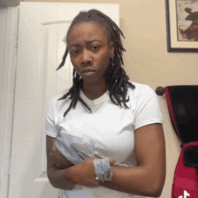 a woman with dreadlocks is standing with her arms crossed in front of a door