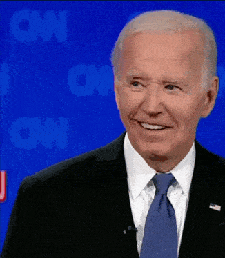 a man in a suit and tie is smiling in front of a cnn sign