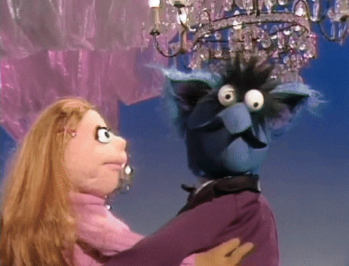 a puppet with big eyes is dancing with a woman