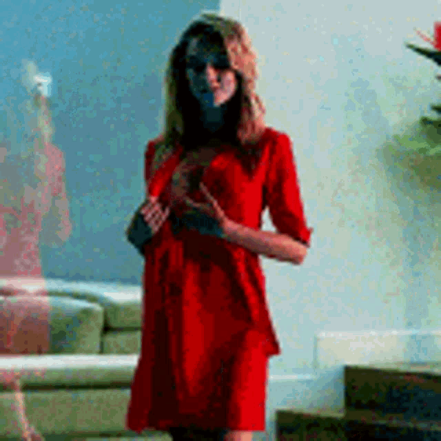 a woman in a red dress is standing in a room