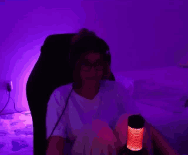a woman is sitting in a chair with a purple light behind her .
