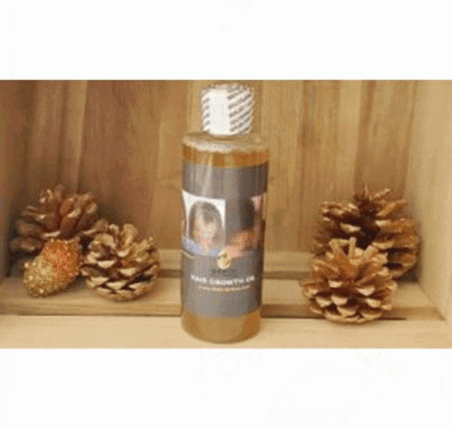 a bottle of hair growth oil is sitting on top of a wooden shelf next to pine cones .