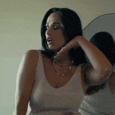 a woman wearing a white tank top and a gold necklace