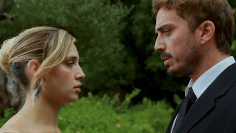 a man and a woman are looking at each other and the man is wearing a suit