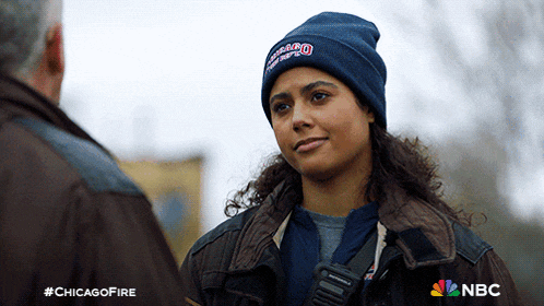 a woman wearing a chicago fire beanie talking to a man