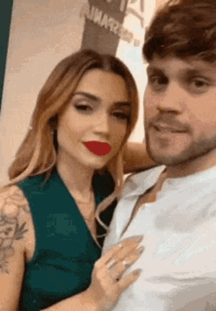 a man and a woman are posing for a picture and the woman has red lipstick