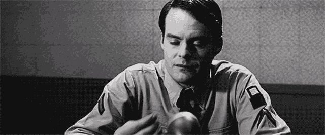 a man in a suit and tie is sitting at a table holding a ball in his hands .