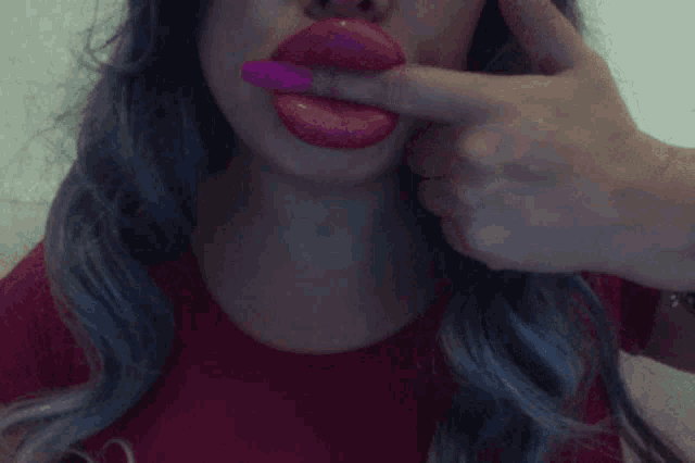 a close up of a woman 's mouth with a pink nail polish