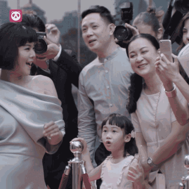 a group of people are posing for a picture with a pink panda logo in the background