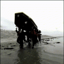 a group of people carrying a large object on a beach with the letter n on it