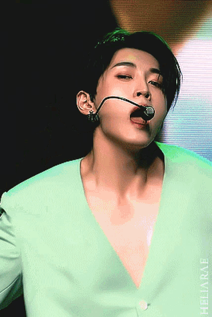 a close up of a man wearing a green jacket and a microphone in his mouth