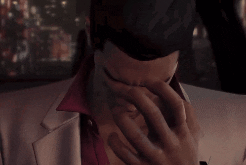 a man in a suit is covering his face with his hand