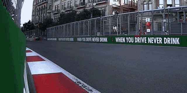 a race car is going down a track with a sign that says when you drive never drink