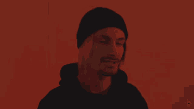 a man with a beard wearing a black hat and a black hoodie