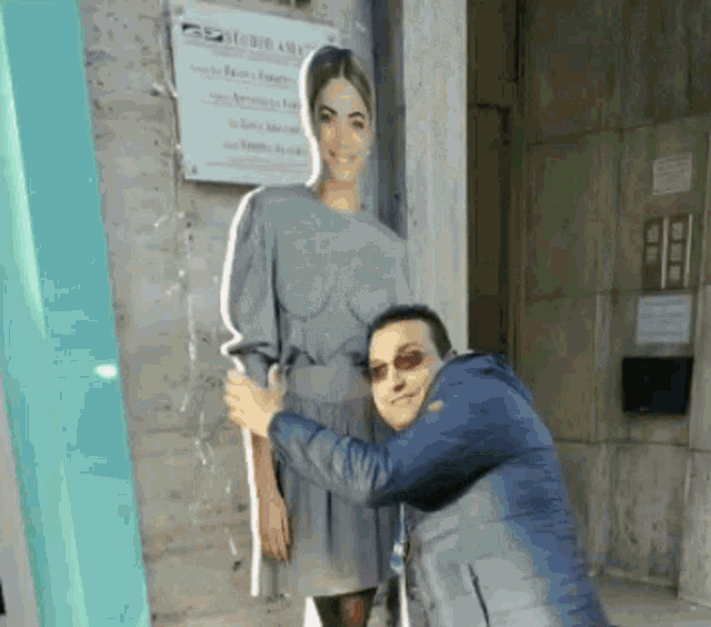 a man is hugging a cardboard cutout of a woman in a grey dress