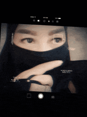 a woman wearing a black hijab is taking a picture with a mnl 1/125 open 3db setting