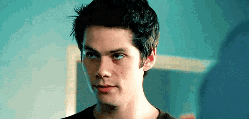 a close up of a young man 's face with blue eyes and a black shirt .