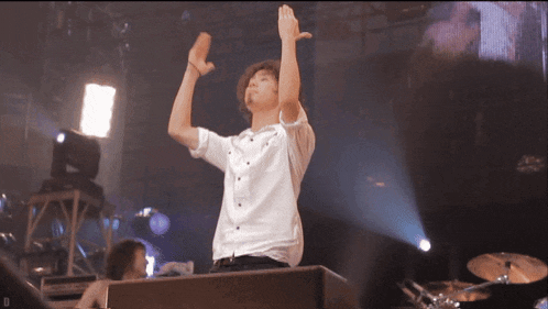 a man stands on a stage with his arms in the air