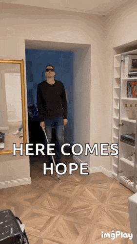 a man walking with a cane in a hallway with the words here comes hope on the bottom