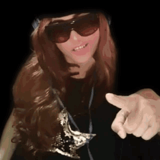 a woman wearing sunglasses and a hat is pointing her finger