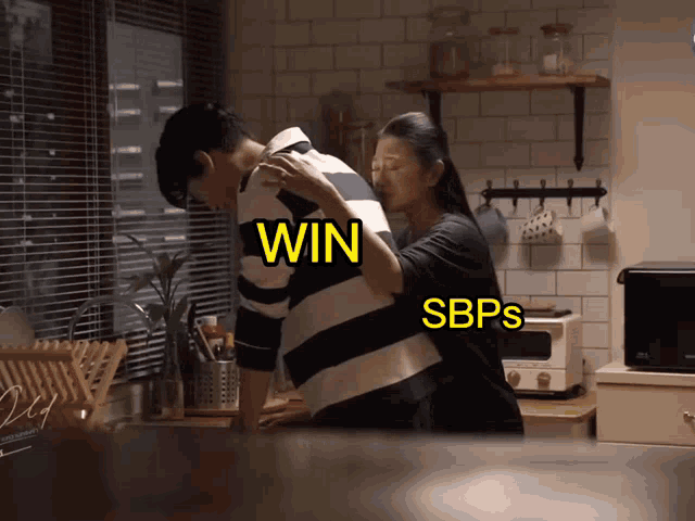 a woman holds a man 's back in a kitchen with the words win sbps on the bottom