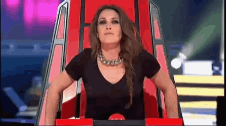 a woman is sitting in a red chair with her arms outstretched .