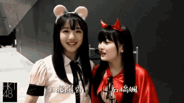 a girl wearing a mouse headband and a girl wearing devil horns