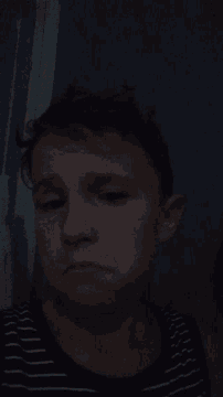 a man in a black and white striped shirt is laying down in the dark