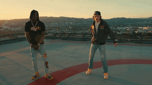 two men standing on a rooftop with one wearing a jacket that says ' abercrombie & fitch '