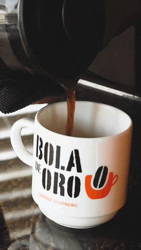 a cup of bola de oro coffee is being poured into a cup
