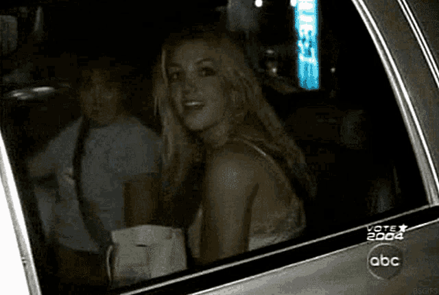 a woman is sitting in the back seat of a car that says vote 2004 on the side