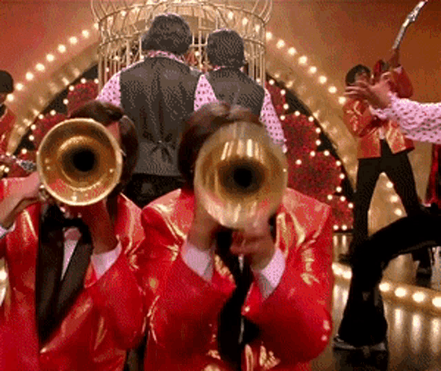 a group of people playing trumpets in front of a stage