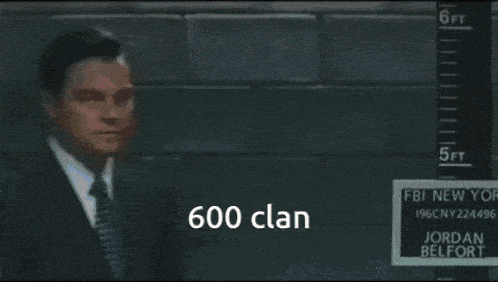 a man in a suit and tie is standing in front of a sign that says 600 clan