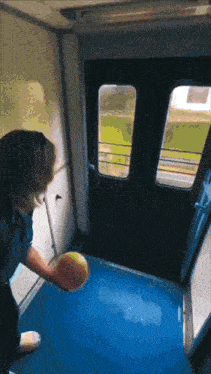 a woman is holding a yellow object in front of a train door