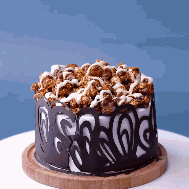 a cake with chocolate icing and popcorn on top is on a wooden cutting board