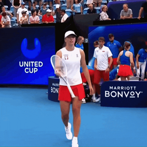 a woman is holding a tennis racquet in front of a united cup banner