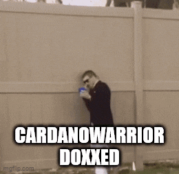 a man in a suit and white pants is standing in front of a wall with the words cardanowarrior doxxed on it .
