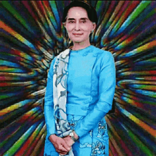 a woman in a blue dress is standing in front of a rainbow background