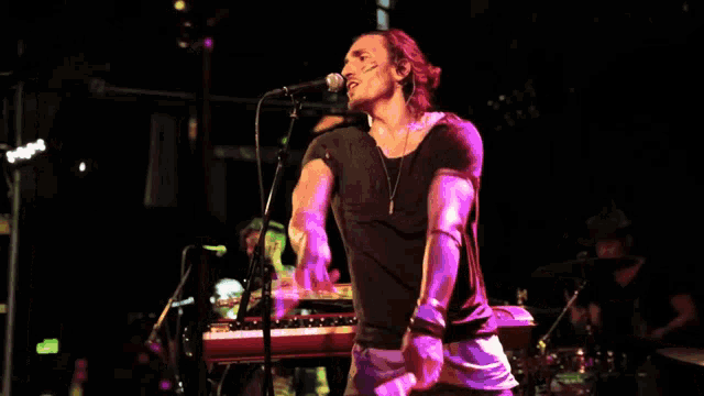 a man playing drums and singing into a microphone on a stage