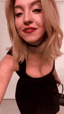 a woman in a black dress is taking a selfie with her breasts visible .