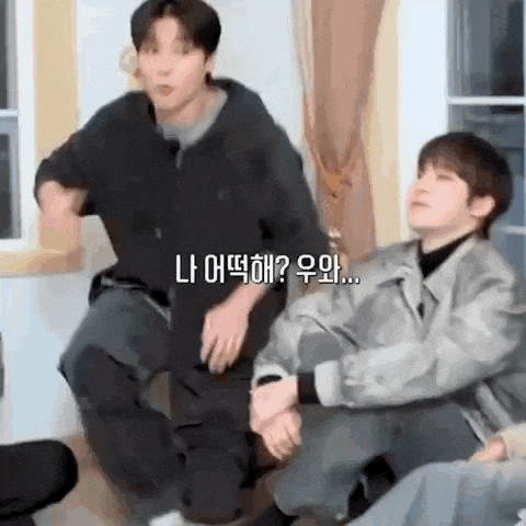 two men are sitting next to each other in a living room .
