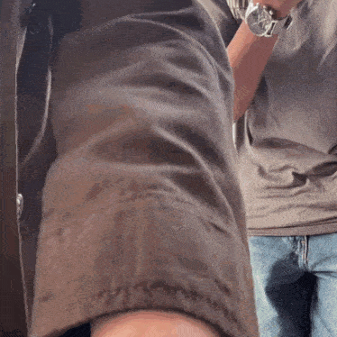 a man wearing a watch is standing next to another person