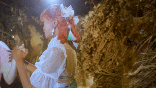 a woman with red hair is standing in front of a pile of leaves