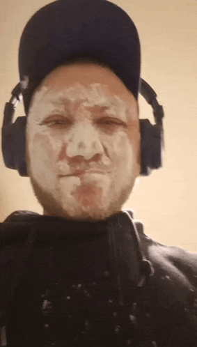 a man wearing headphones and a hat has a white face painted on it